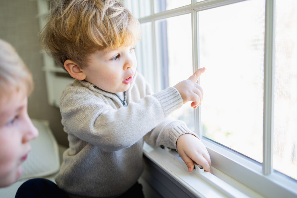 little boy pointing out window during in home family photo session